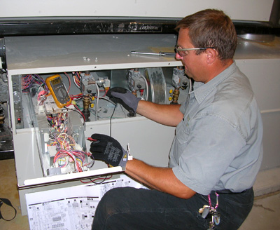 Stuart Mechanical's local HVAC technician performing maintenance on a furnace unit