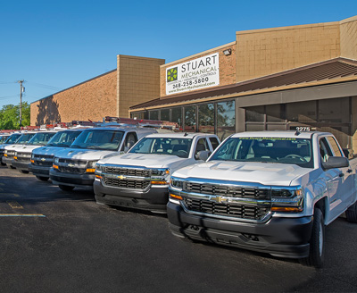 Commercial HVAC technicians from Stuart Mechanical with trucks outside office